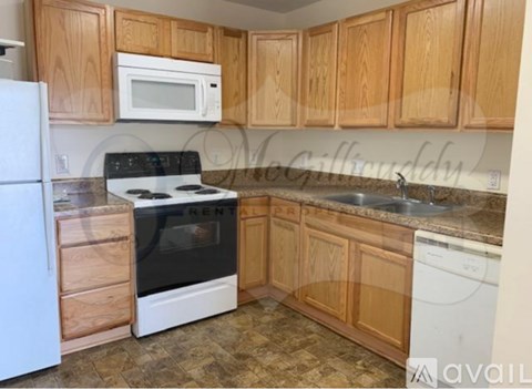 A kitchen with wooden cabinets and a white fridge.