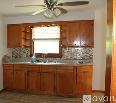 A kitchen with wooden cabinets and a fan on the ceiling.