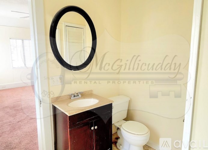 A bathroom with a toilet, sink and mirror.