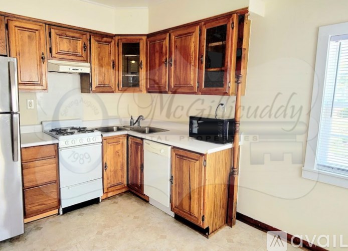 A kitchen with wooden cabinets and a white stove top oven.