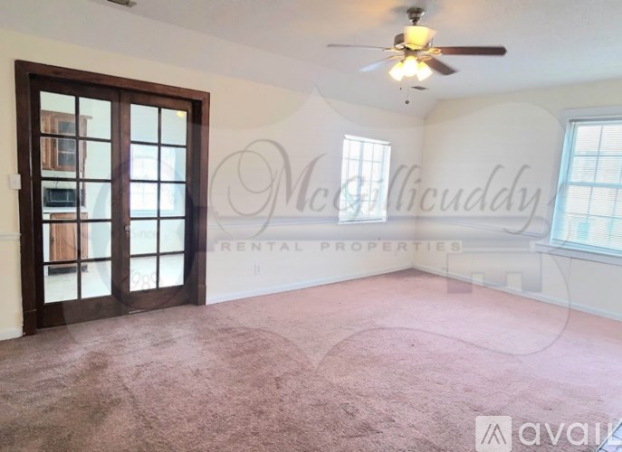 A room with a carpeted floor and a ceiling fan.
