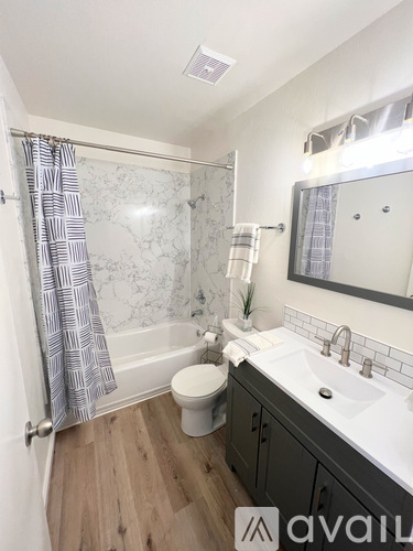 A bathroom with a marble patterned shower and a white toilet.