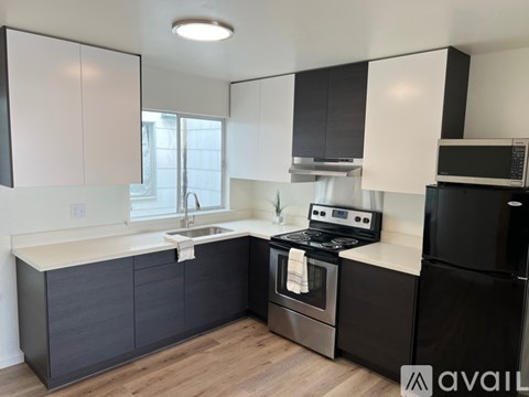 A modern kitchen with black and white cabinets and stainless steel appliances.