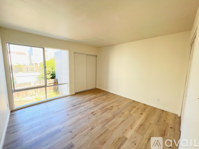A room with wooden flooring and a sliding glass door leading to a balcony.