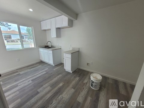 A kitchen with white cabinets and a wooden floor.