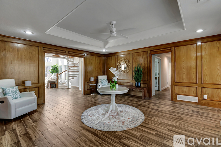 A spacious room with wooden walls and a white ceiling fan.