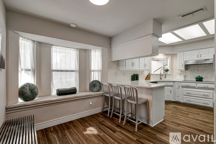 A kitchen with white cabinets and a wooden floor.