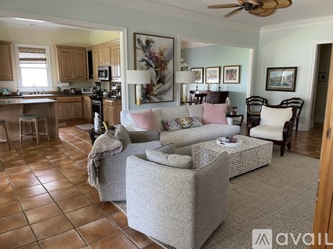 A living room with a grey couch and a brown tiled floor.