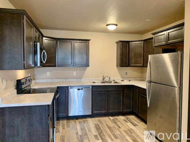 A kitchen with dark wood cabinets and a stainless steel refrigerator.