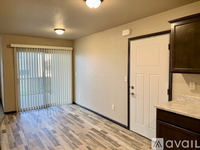 A room with a tiled floor, a window with blinds, a white door, and a cabinet.