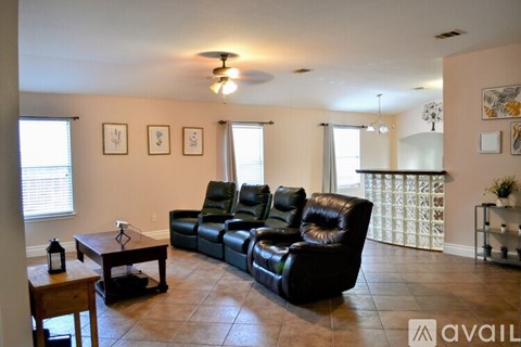 A living room with a black leather couch and a wooden coffee table.