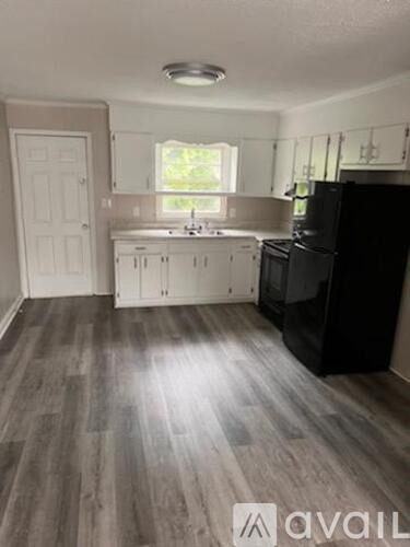 A kitchen with a black refrigerator and wooden floors.