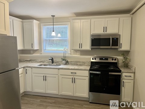 A kitchen with white cabinets and a stainless steel refrigerator.