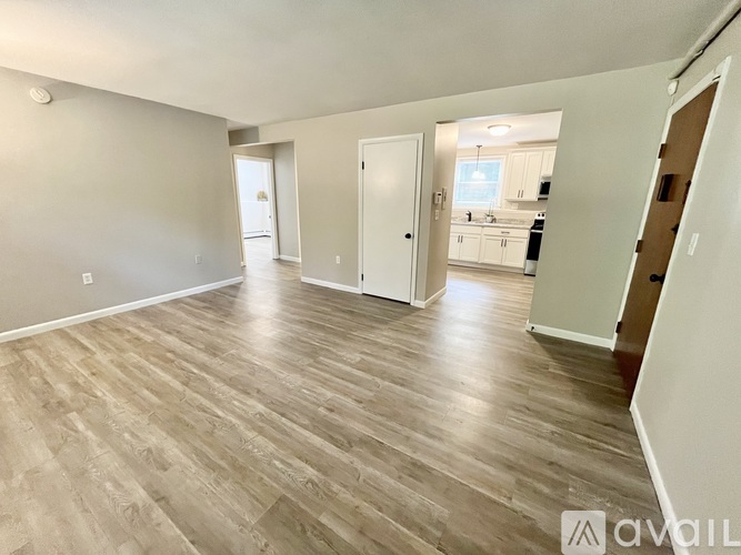 A spacious room with wooden flooring and white walls.