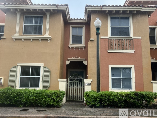 A brown and beige two story townhouse with a black gate and a lamp post in front.