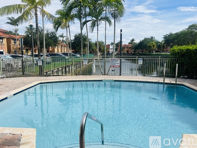 A pool surrounded by a fence with palm trees in the background.
