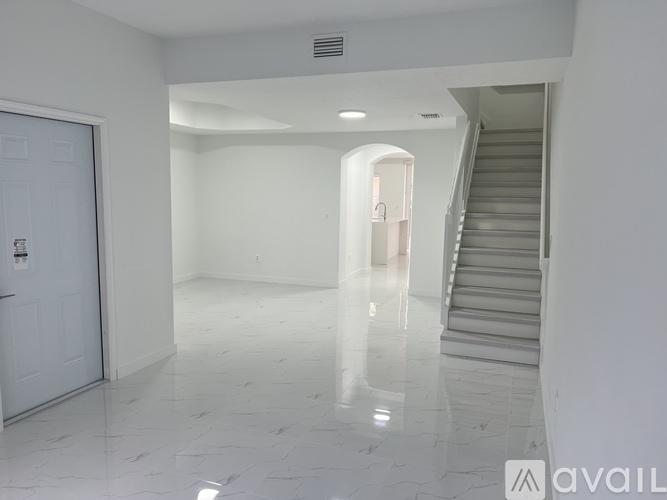 A spacious, empty room with a staircase and a door.