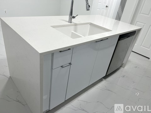 A white kitchen with a sink and cabinets.