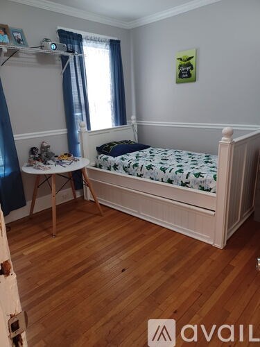 A bedroom with a bed, a desk, and a window with blue curtains.