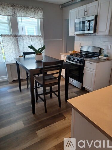 A kitchen with a table and chairs in the foreground and a stove and cabinets in the background.