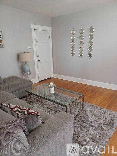 A living room with a grey couch and a glass coffee table.