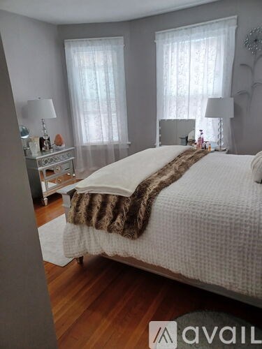 A bedroom with a large bed and a nightstand with a lamp.