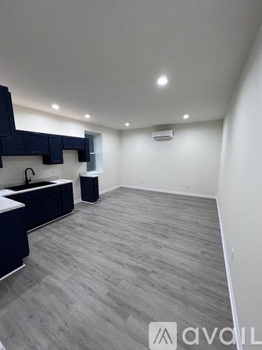 A modern kitchen with dark blue cabinets and a wooden floor.