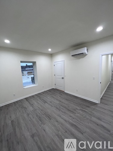 A room with grey flooring and a window showing a building outside.
