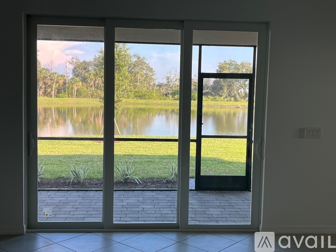 A glass door with a view of a lake and greenery outside.