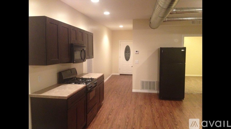 A kitchen with dark wood cabinets and a black refrigerator.