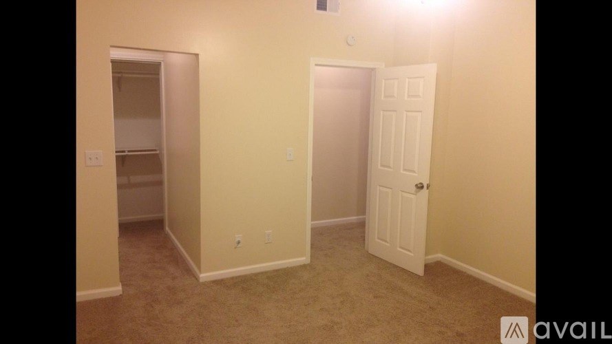 A room with a carpeted floor and two doors, one of which is open.