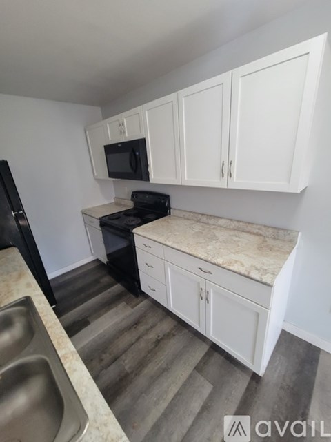 A kitchen with white cabinets and a black fridge.