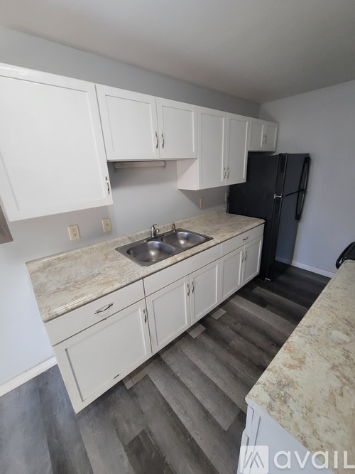 A kitchen with white cabinets and a black refrigerator.