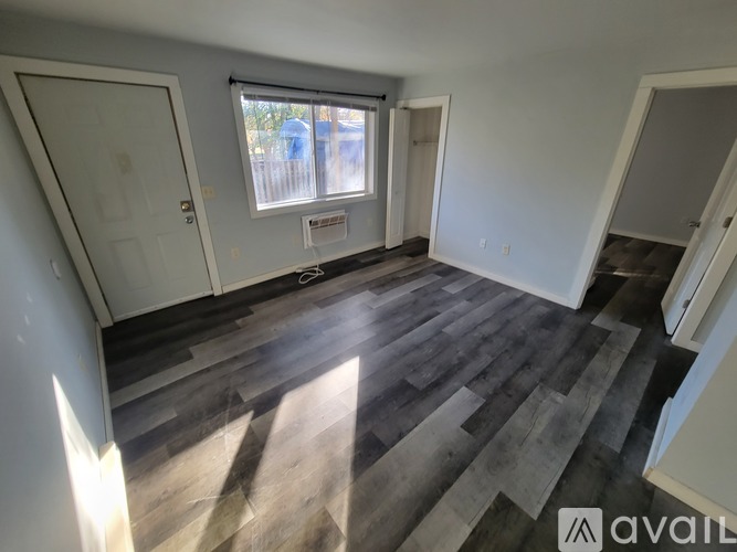A room with wooden flooring and a window with blinds.