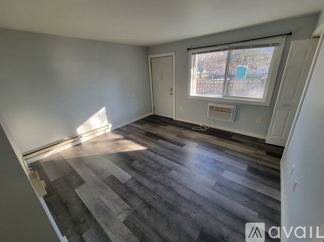 A room with wooden flooring and a window overlooking a blue object outside.