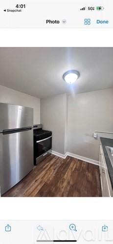 A kitchen with a stainless steel refrigerator and wooden flooring.