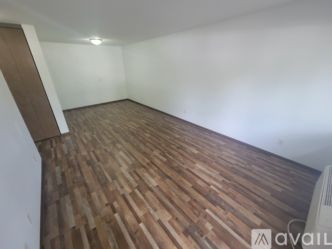 A room with wooden flooring and a white wall.