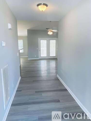 A room with a white door and wooden floor.