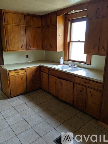 A kitchen with wooden cabinets and a window.