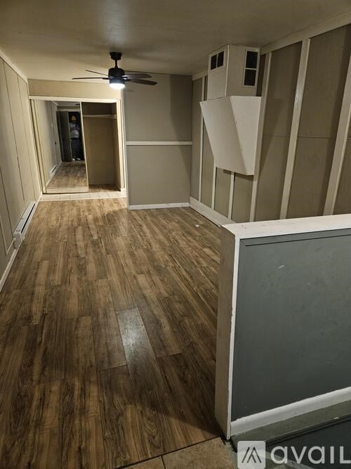 A room with wooden flooring and a ceiling fan.