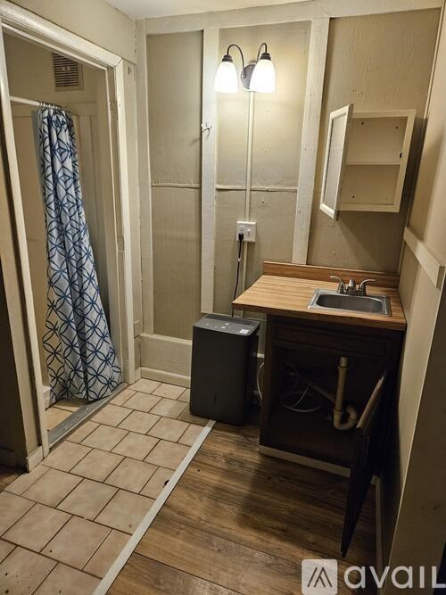 A bathroom with a wooden vanity and a patterned shower curtain.