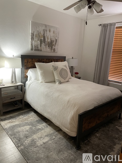 A bedroom with a large bed, a ceiling fan, and a rug on the floor.