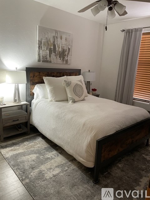 A bedroom with a large bed, a ceiling fan, and a rug on the floor.
