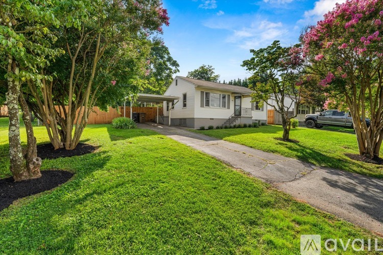A house with a well-maintained lawn and trees in front of it.