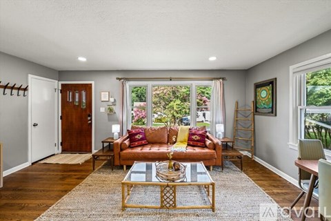 A living room with a couch, coffee table, and a window with a view of the backyard.