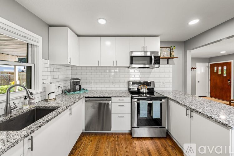 A modern kitchen with white cabinets and a wooden floor.