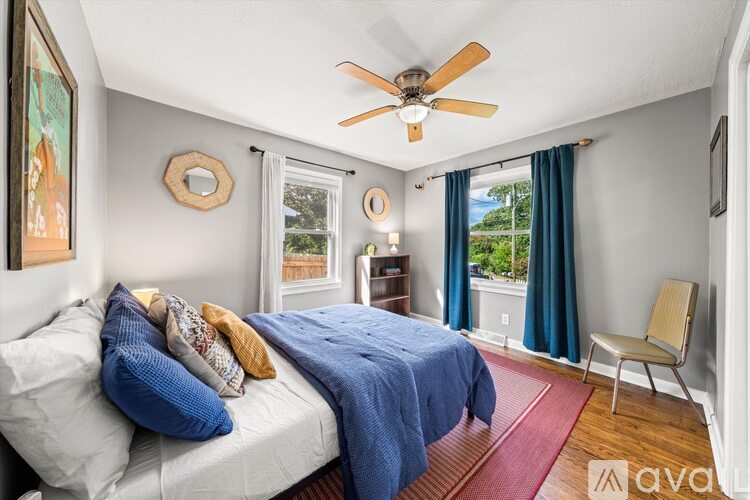 A bedroom with a bed, a chair, and a ceiling fan.