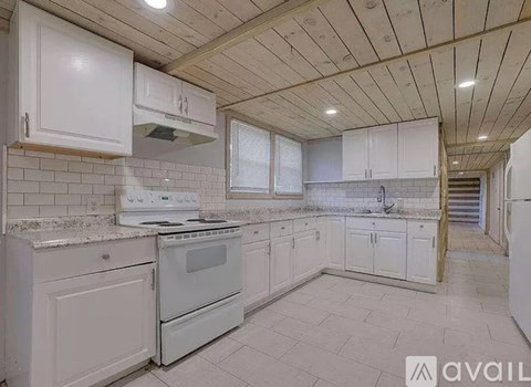 A kitchen with white cabinets and appliances is available for rent.