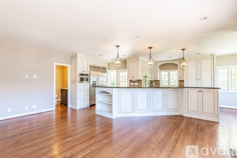 A spacious kitchen with white cabinets and a wooden floor.