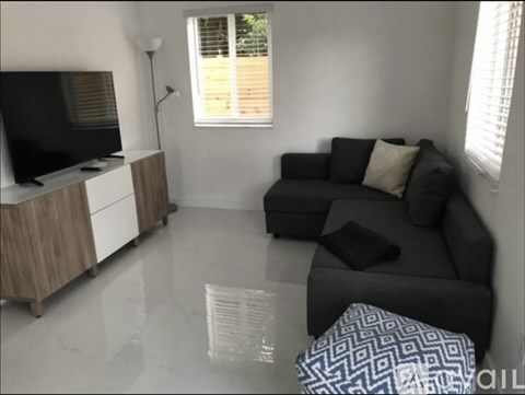 A living room with a black couch and a television.